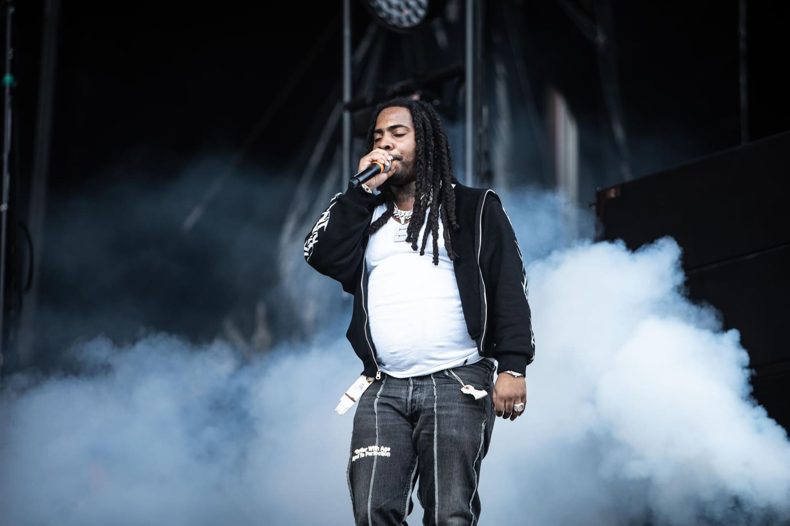 A rapper in a black jacket performs in stage smoke at Dreamville Festival, Raleigh, 2025
