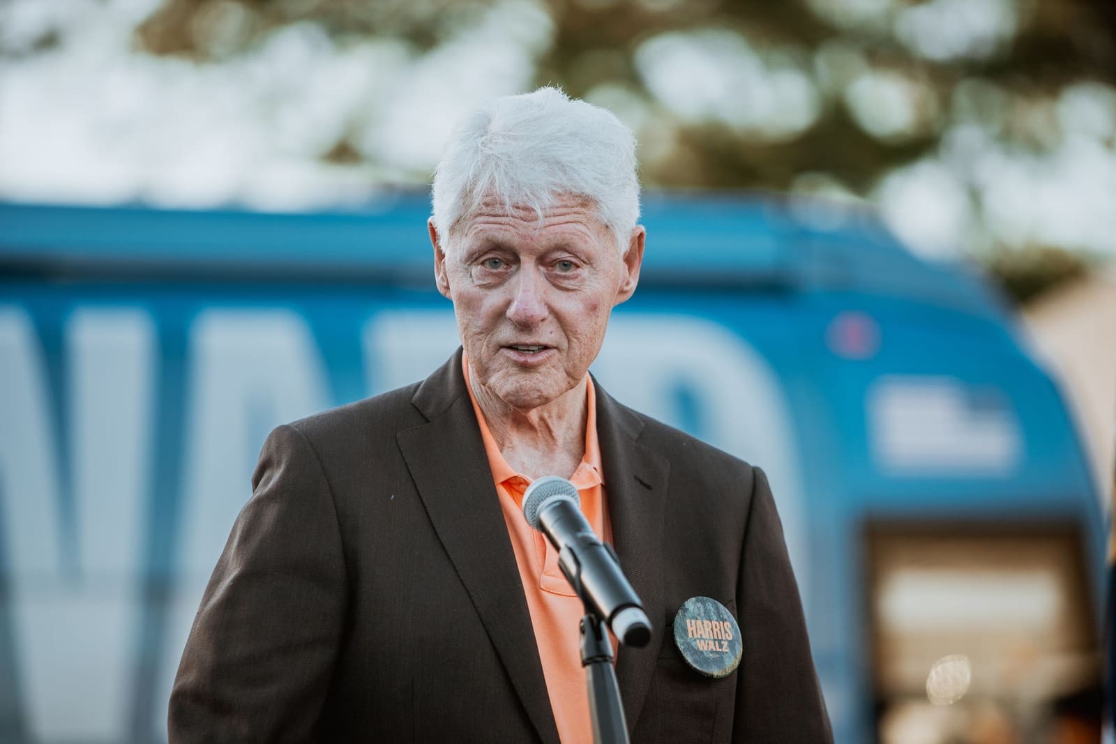 Bill Clinton speaks outdoors in Greenville, NC, wearing a campaign button
