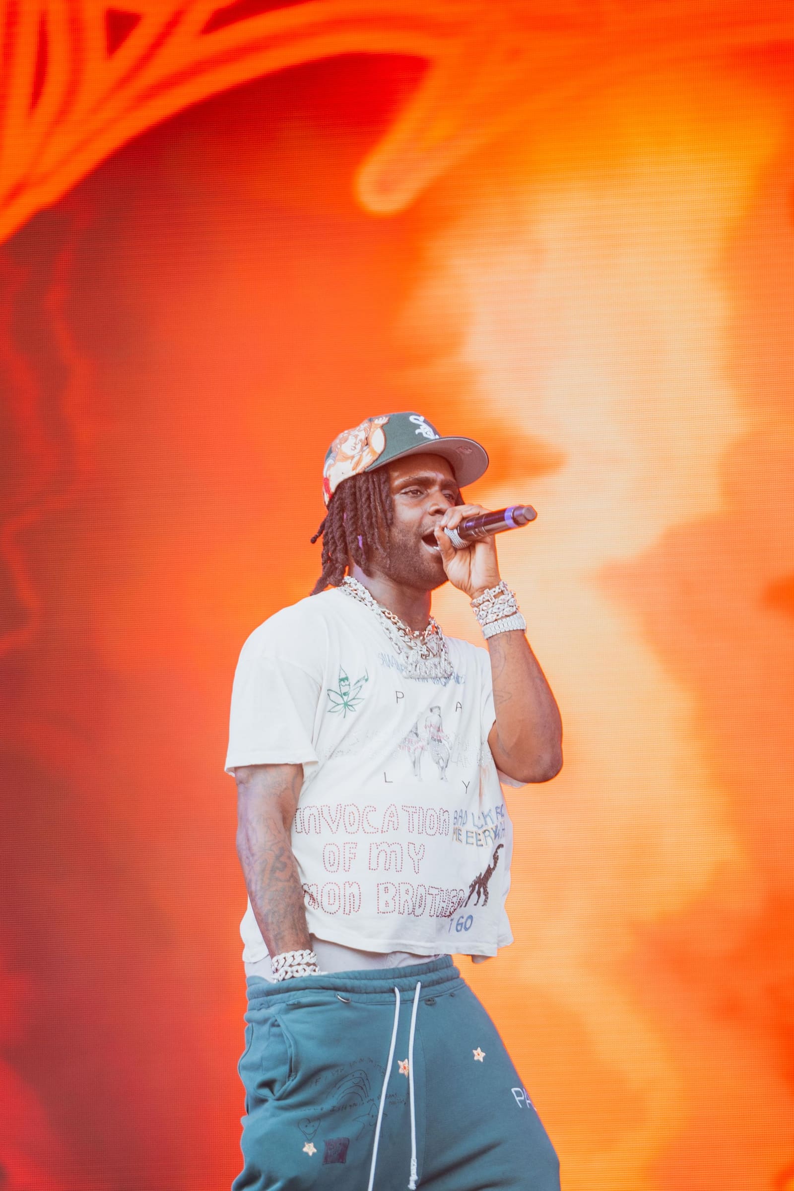 A rapper in a white tee and teal star pants sings at Dreamville Festival, Raleigh, 2025