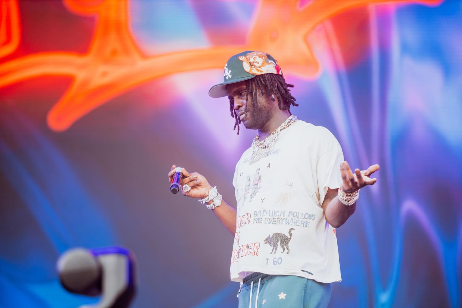 A rapper in a white tee and cap gestures to the crowd at Dreamville Festival, Raleigh, 2025