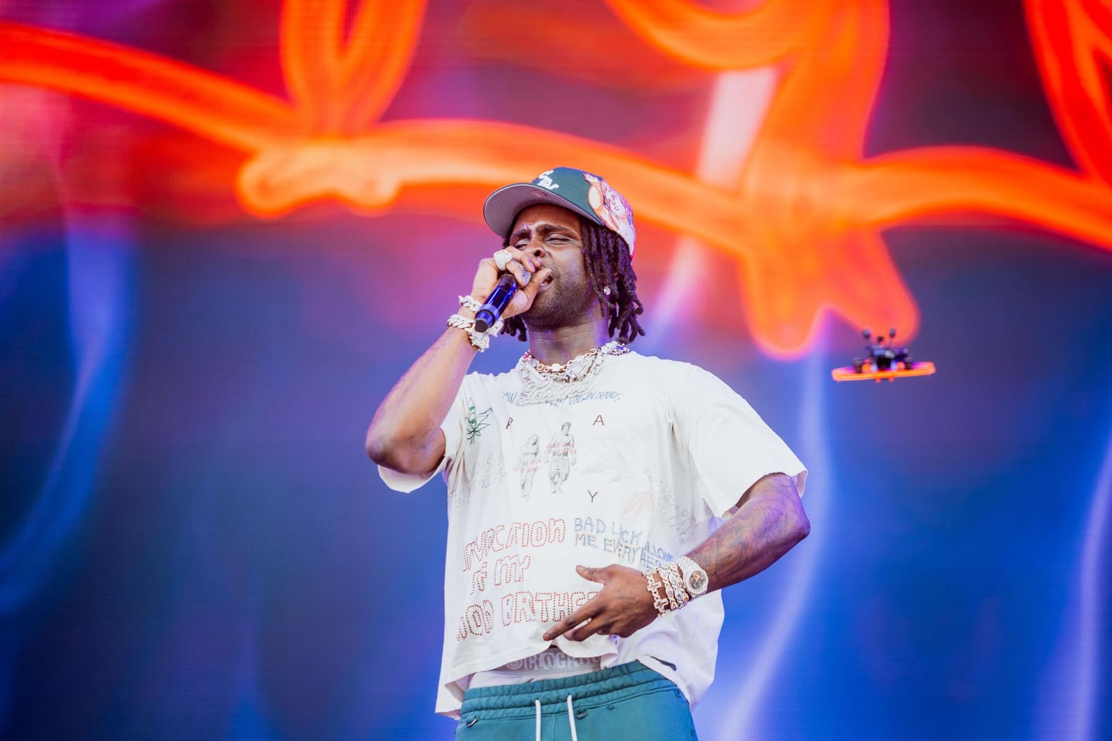 A rapper in a white tee performs against neon lights at Dreamville Festival, Raleigh, 2025