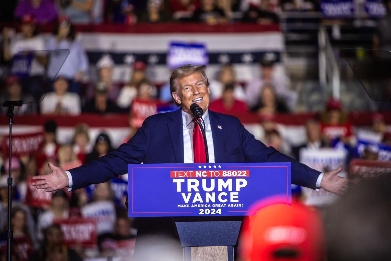 Donald Trump spreads his arms wide while speaking at a packed Trump Vance 2024 rally in North Carolina.