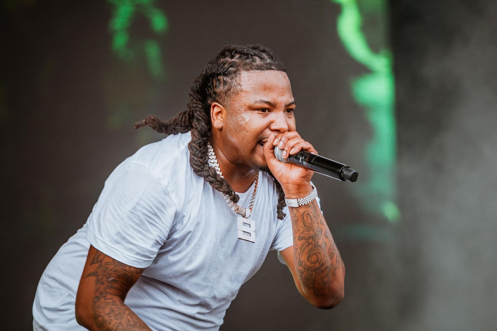 A rapper with dreadlocks and a chain performs outdoors at Dreamville Festival, Raleigh, 2025