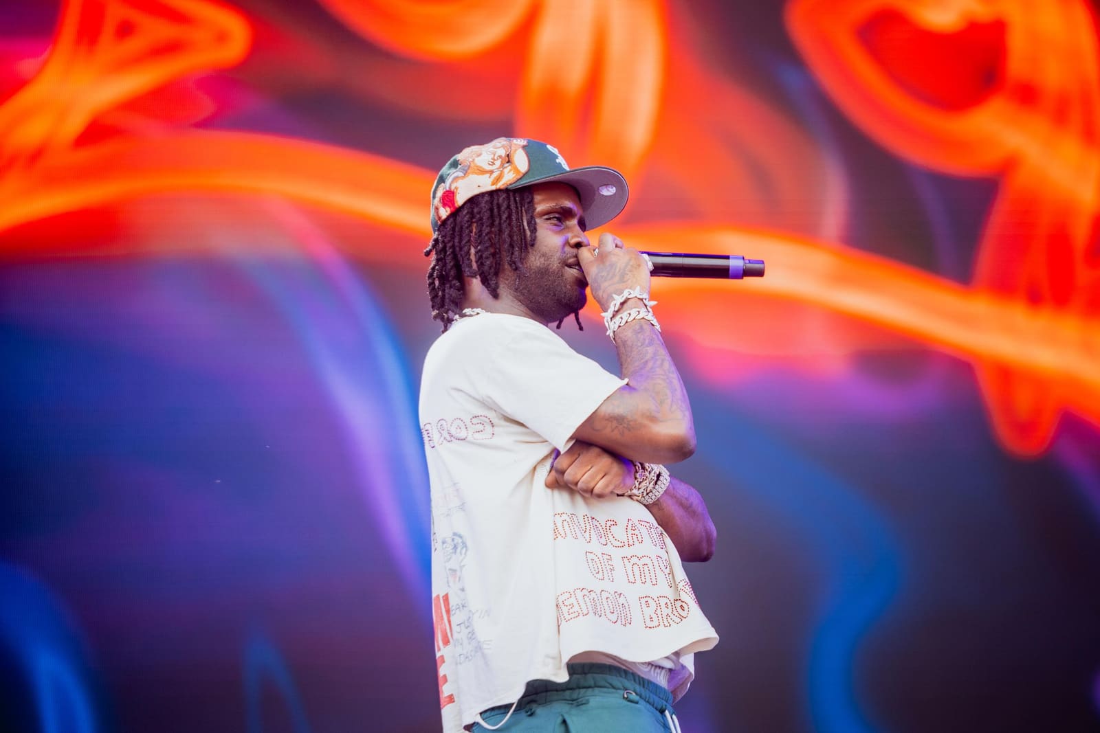 A rapper holds the microphone against neon lights at Dreamville Festival, Raleigh, 2025