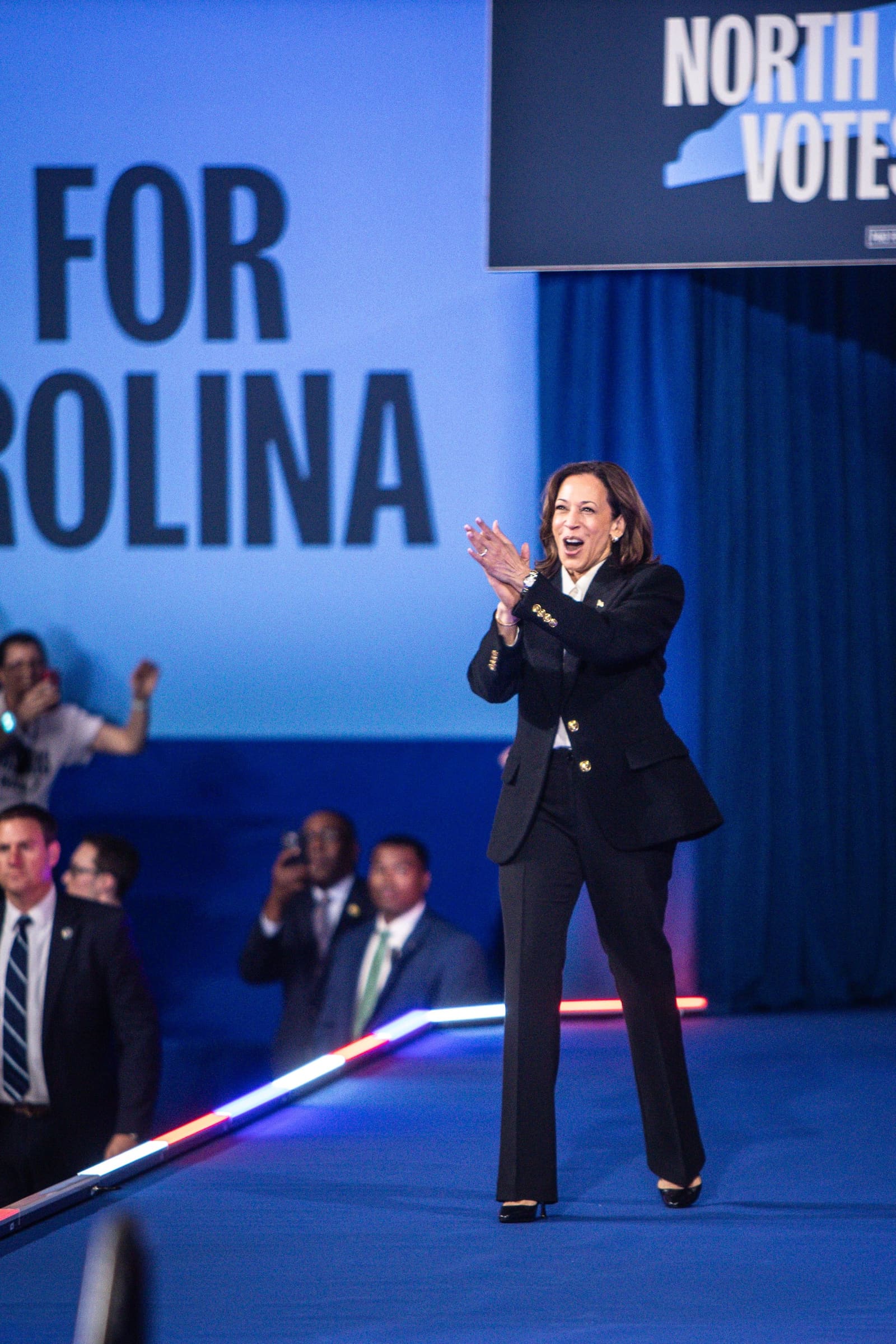 Kamala Harris claps on stage at a North Carolina Votes Early campaign rally.