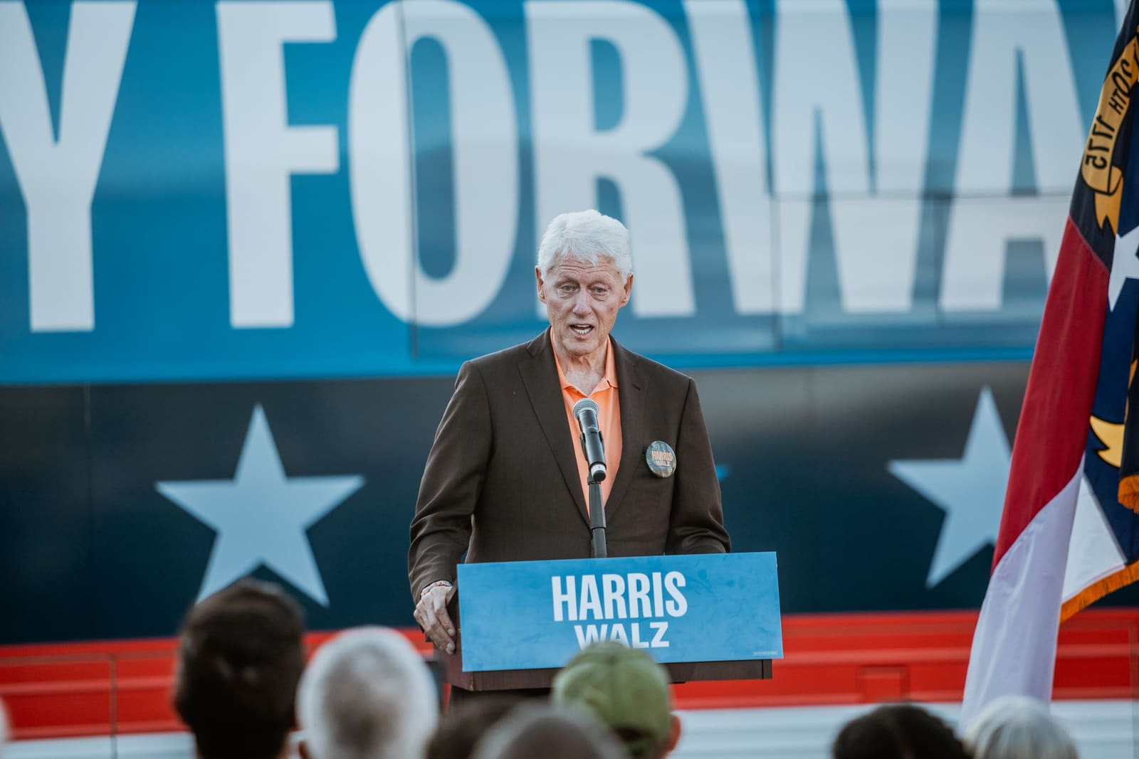 Bill Clinton speaks in front of the blue Forward banner