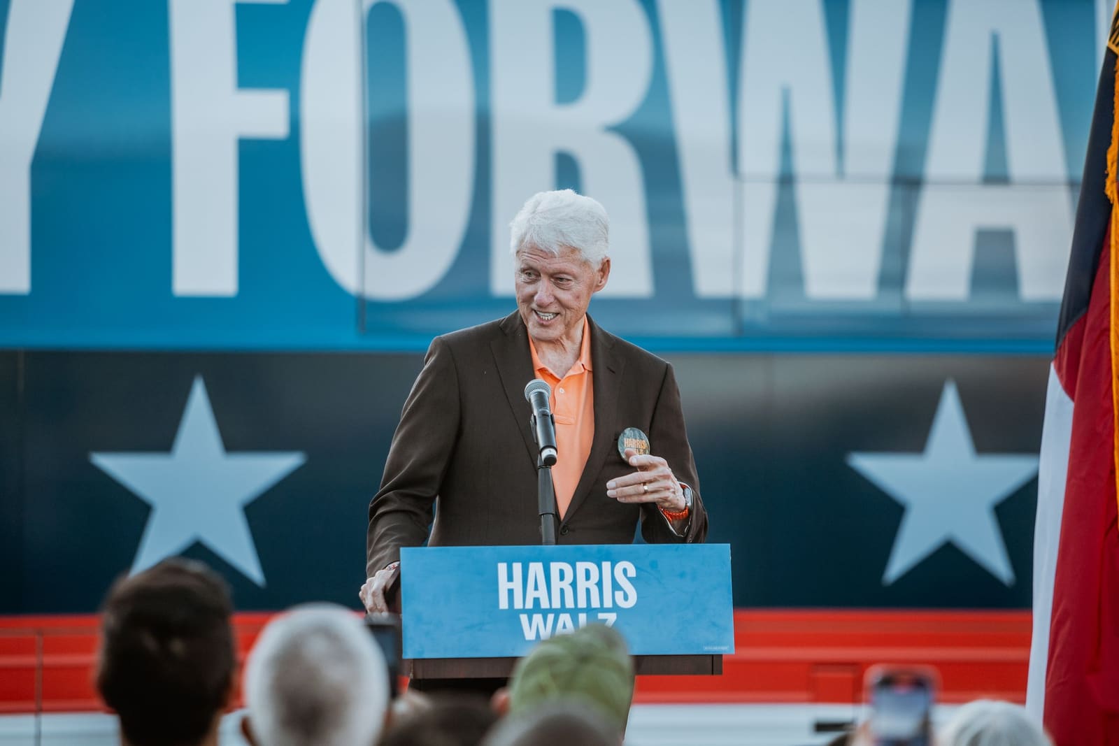 Bill Clinton speaks in front of a blue banner with stars