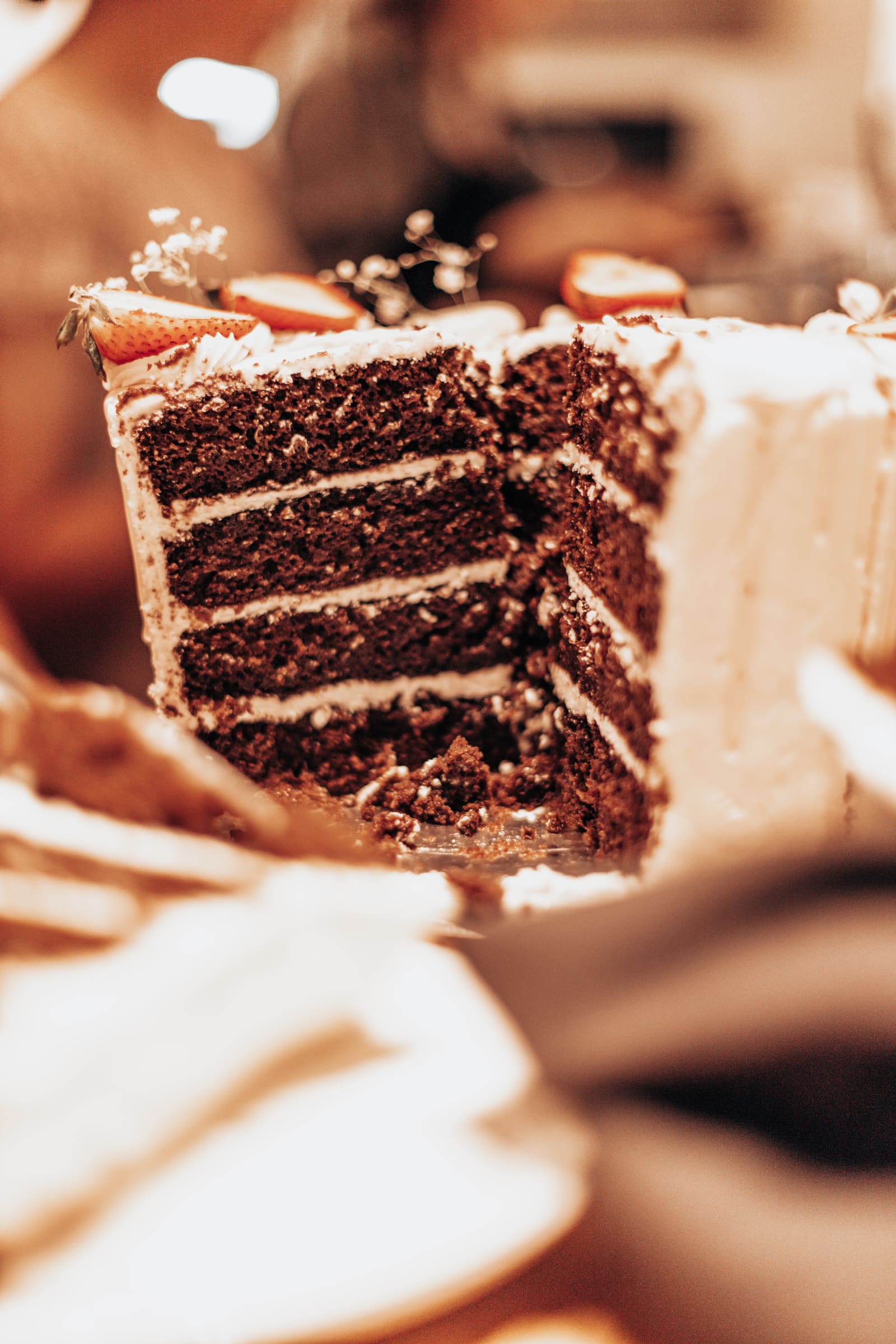 A slice of layered chocolate cake lifted on a fork, warmly lit