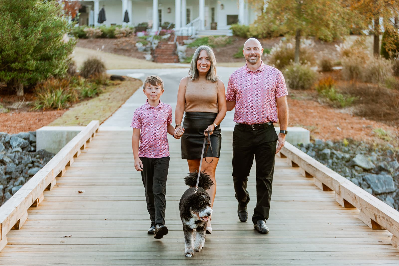 A family walking toward the camera on a wooden boardwalk with their dog