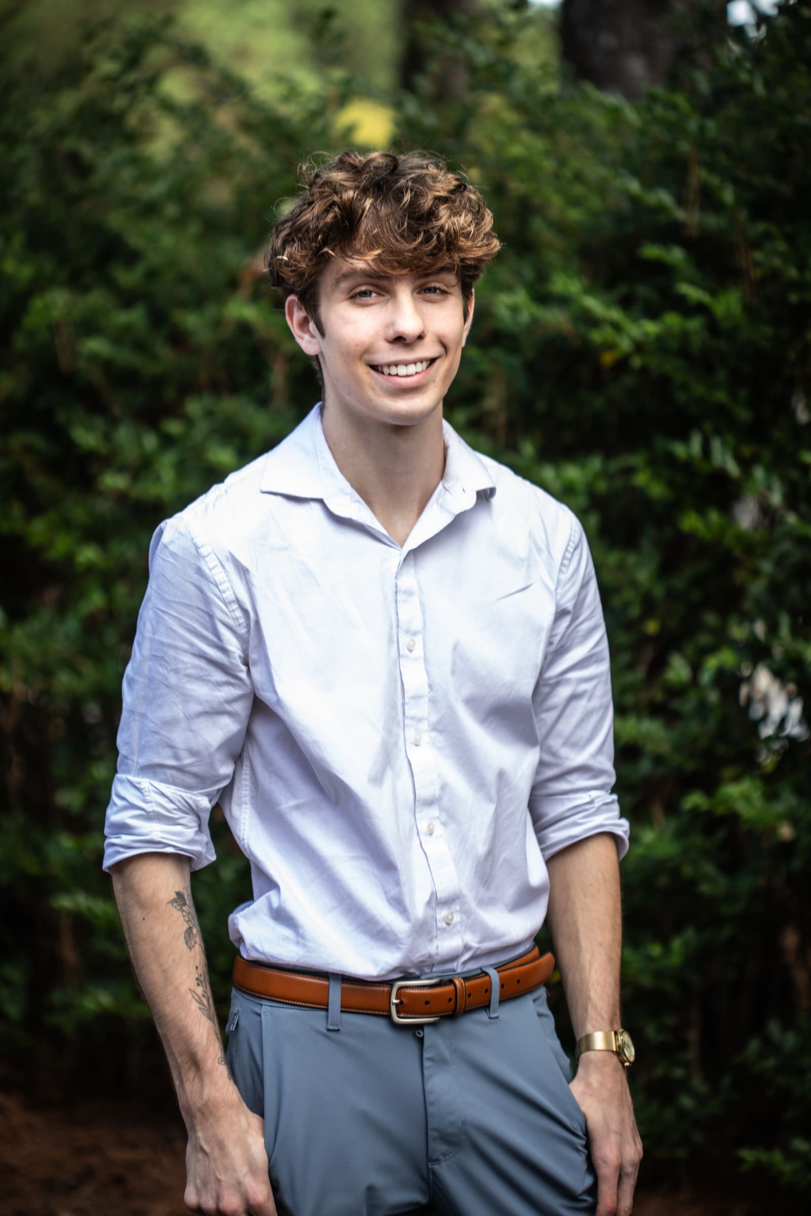 Gabe Key standing outdoors in a white shirt in front of green trees