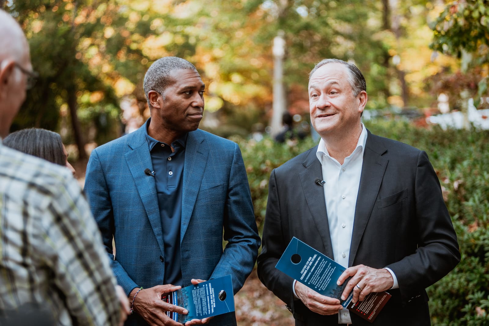 Doug Emhoff and a local host laughing in an autumn yard