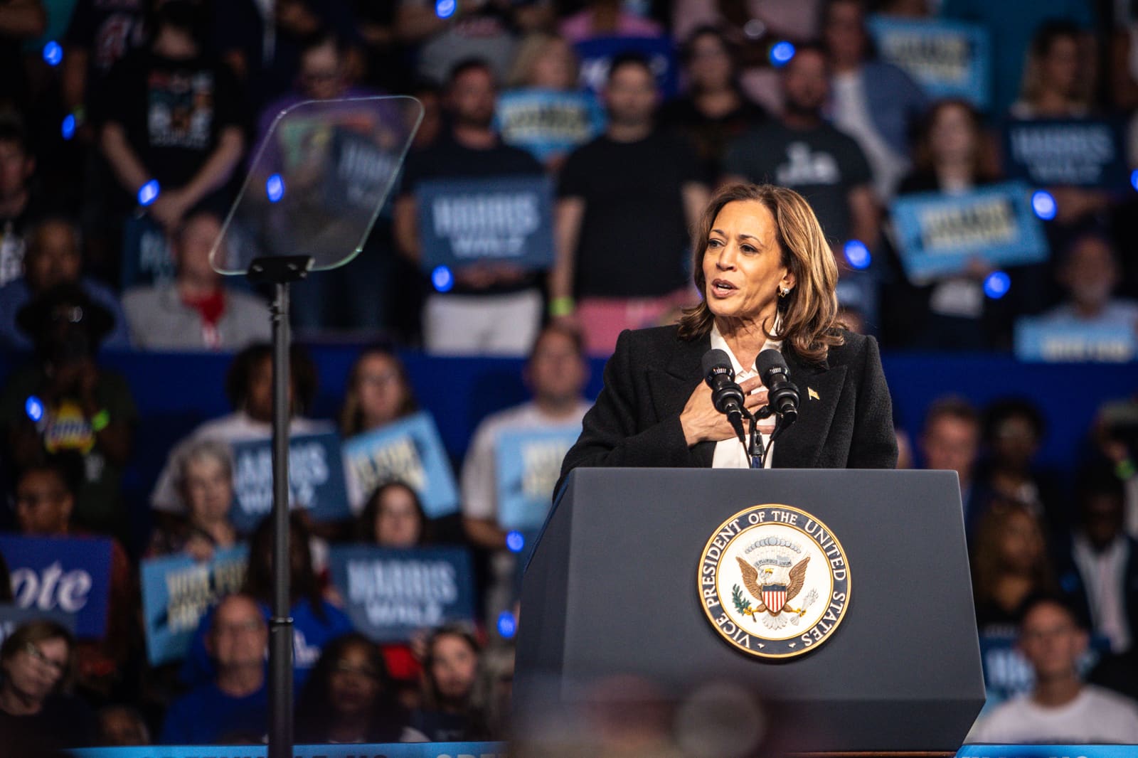 Kamala Harris at the podium with supporters in blue behind her