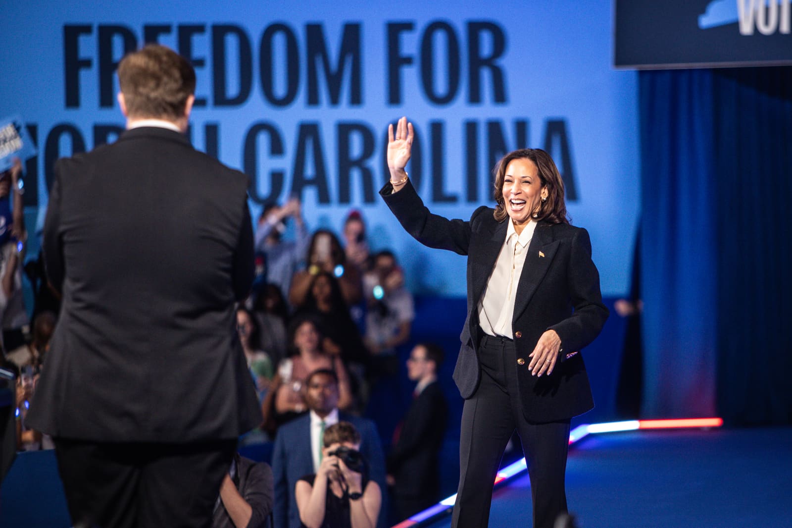 Kamala Harris walking out on stage in front of a Freedom for North Carolina backdrop