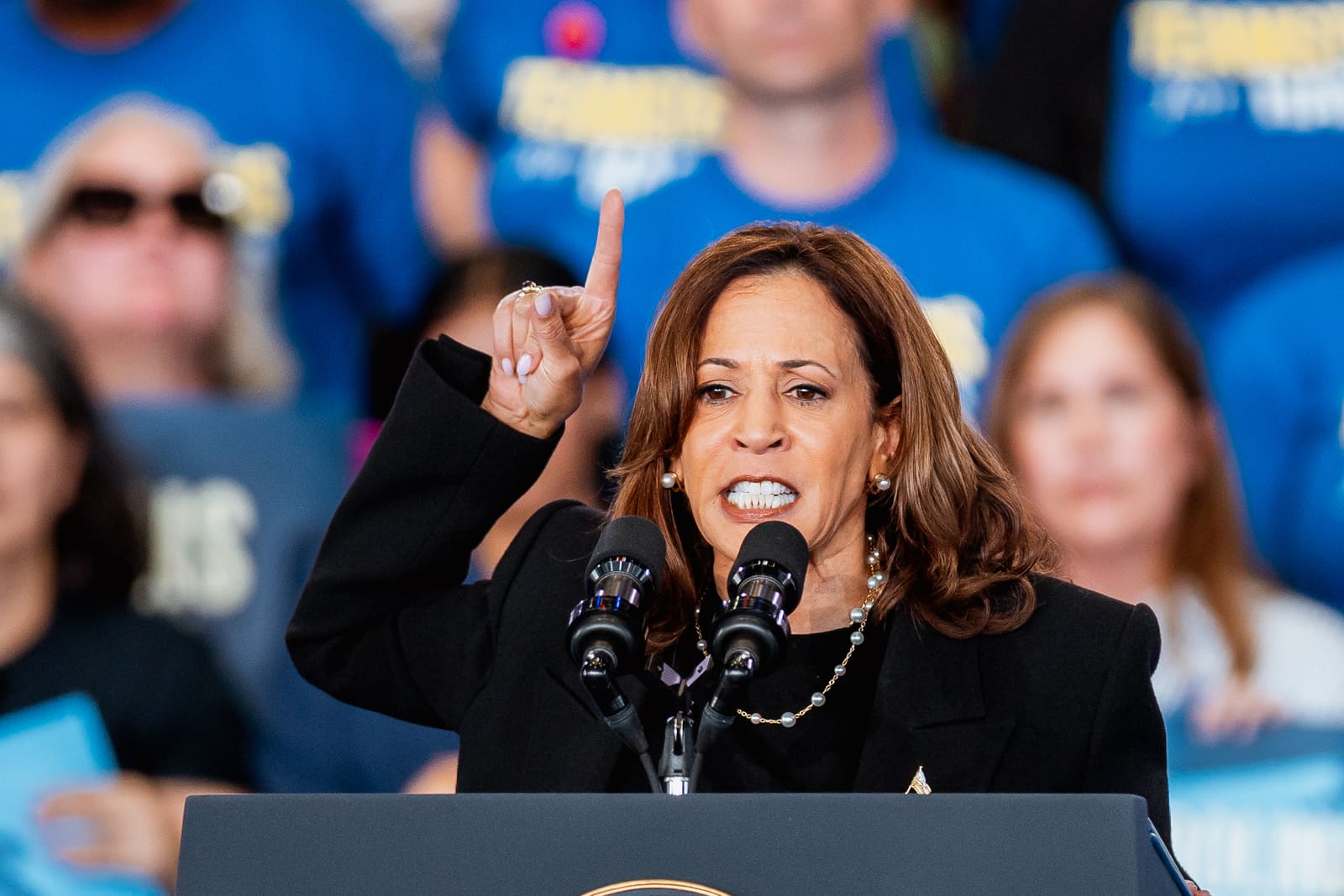 Kamala Harris speaking with a raised finger at the podium
