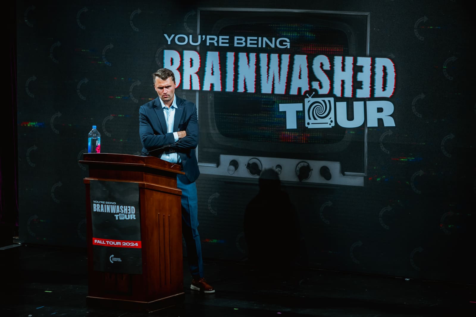 Charlie Kirk standing beside the podium on stage