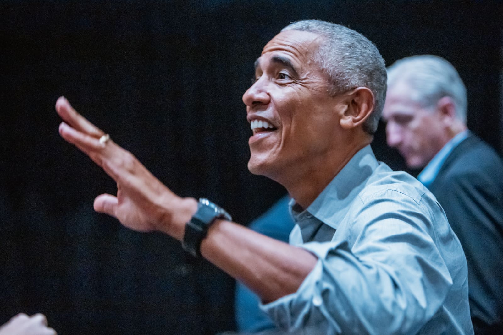 Barack Obama laughing and gesturing mid-speech