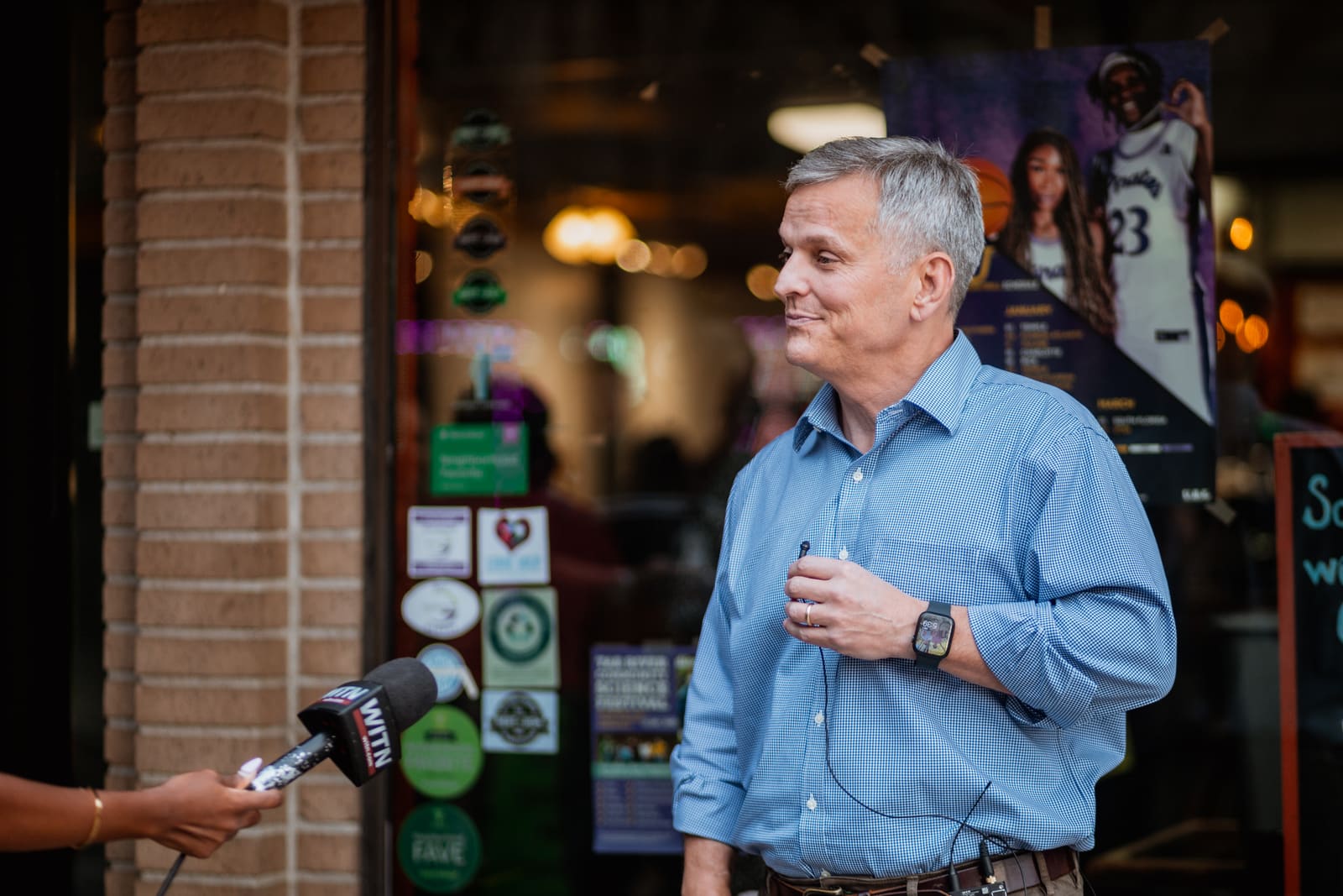 Josh Stein speaking to a reporter outside a downtown shop