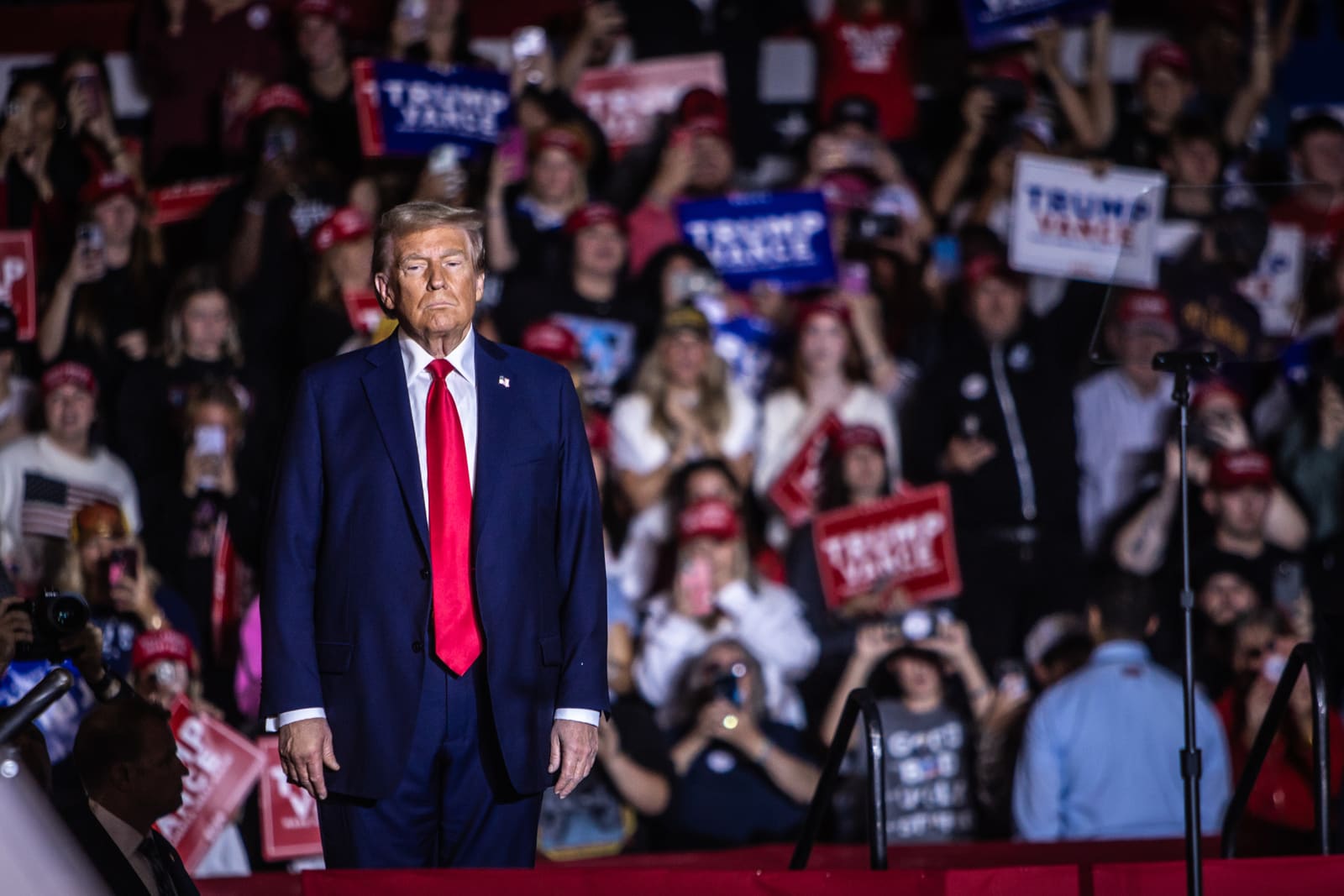 Donald Trump standing alone in a crowd of raised phones