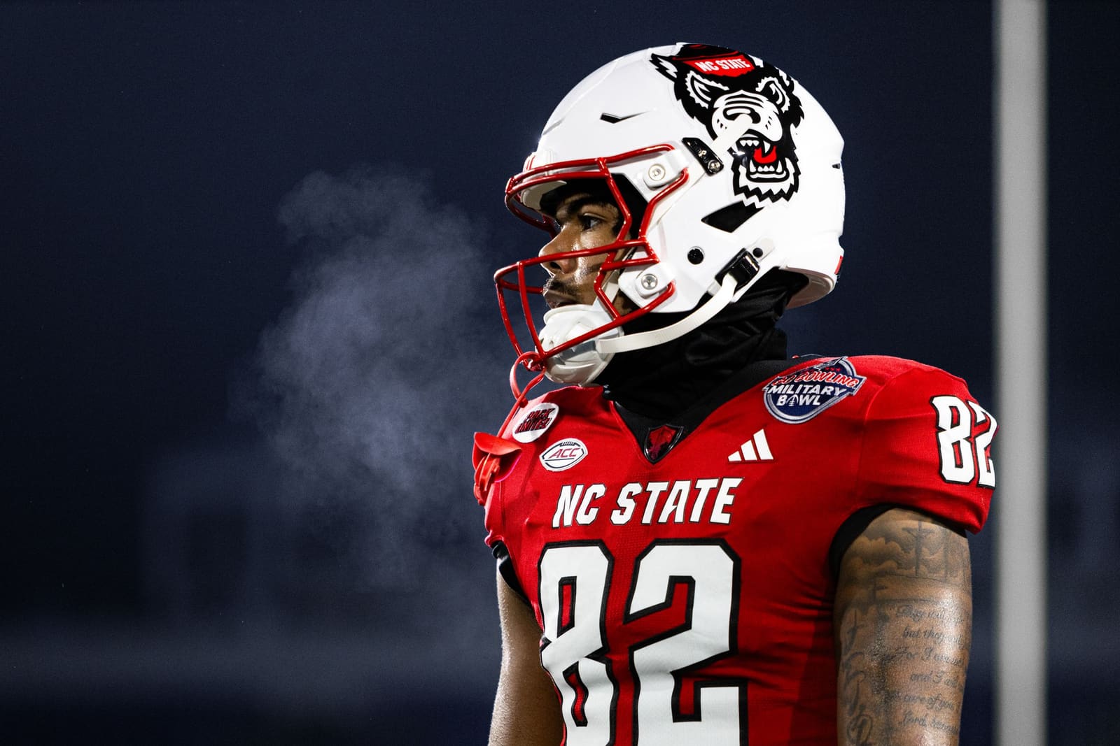 NC State Wolfpack football player number 82 in red uniform with breath visible in cold game night air.