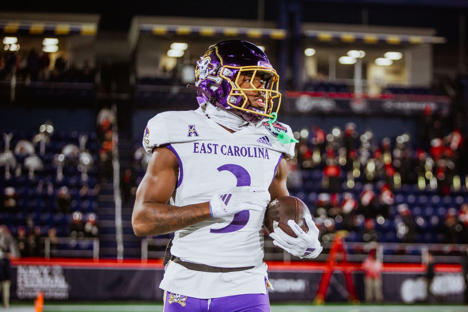 East Carolina Pirates wide receiver number 3 in purple uniform warming up on field during bowl game.