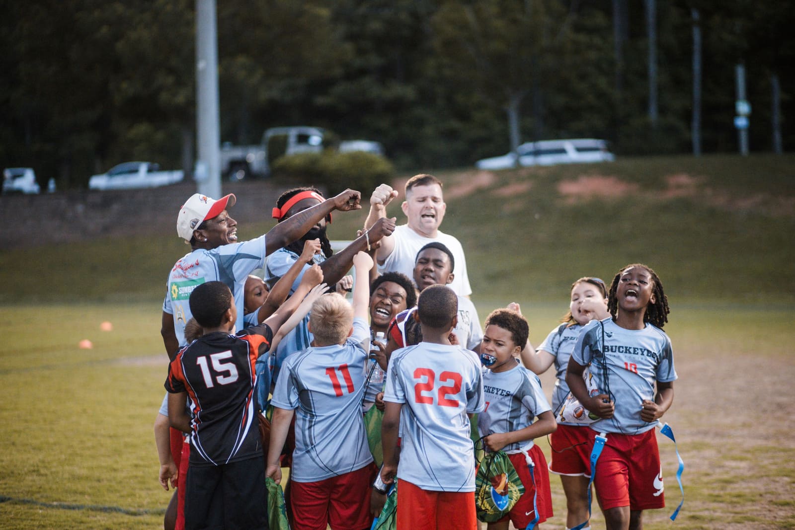 Youth flag football team celebrates with a group huddle and high fives after a game.